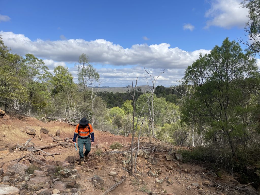 Ecologist walking up rocky hill carrying an ipad.